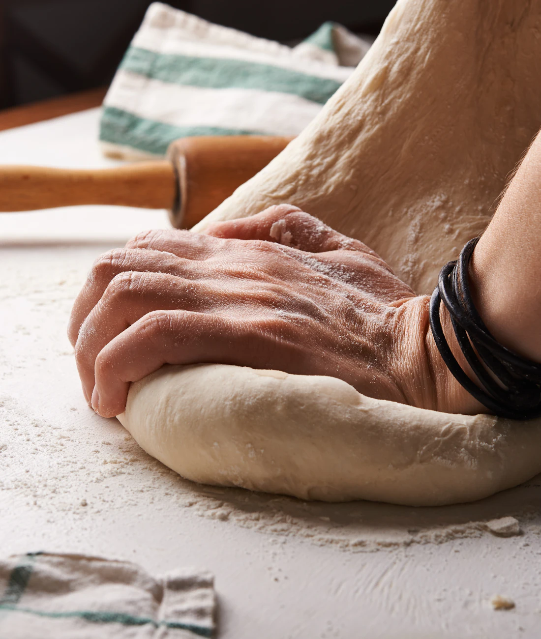 Hands shaping dough with a rolling pin